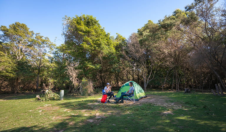 Two campers sitting outside their tent at Hobart Beach campground, Bournda National Park. Photo: Daniel Tran/DPIE