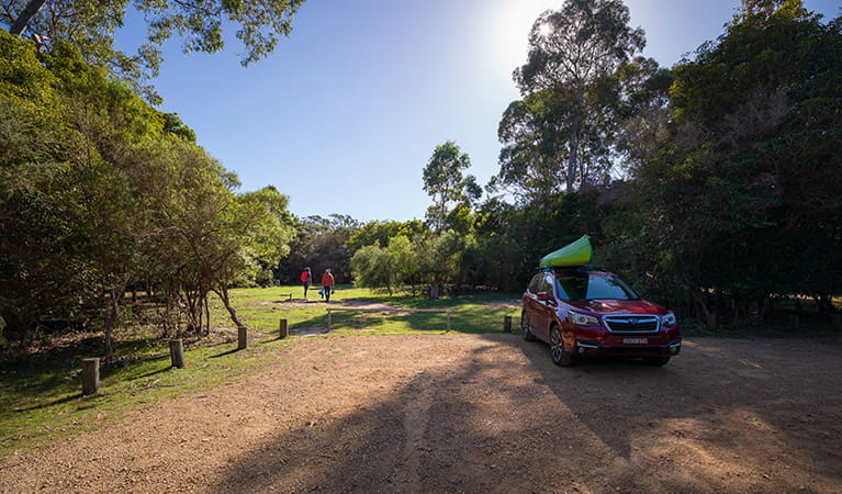 Two people walking away from a car parked at Hobart Beach campground, Bournda National Park. Photo: Daniel Tran/DPIE