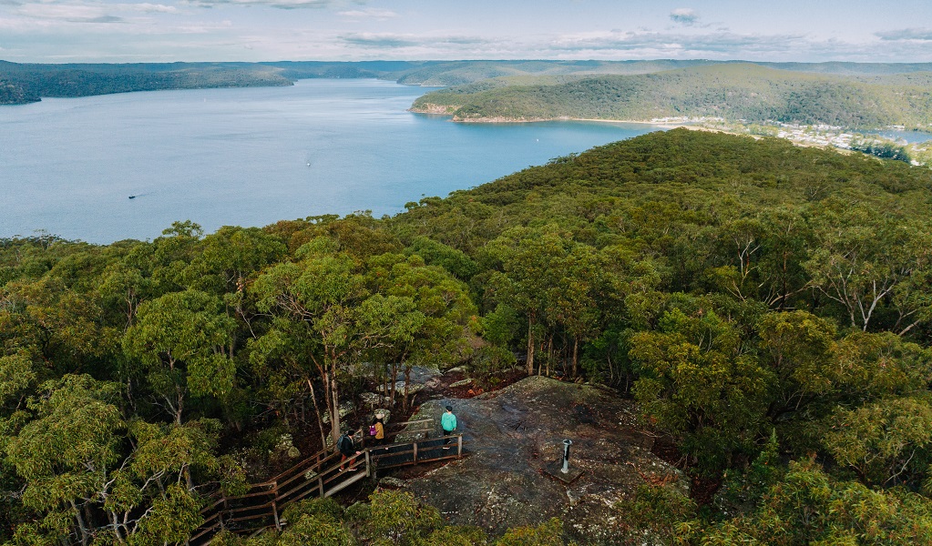 Aerial view of hikers along  Warrah Trig walking track framed by the picturesque Hawkesbury River. Photo: Remy Brand/DCCEEW © Remy Brand