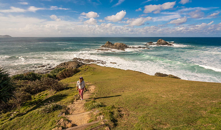 A woman walking up a hill along Three Sisters walking track with the ocean in the background in Broken Head Nature Reserve. Photo: John Spencer &copy; OEH