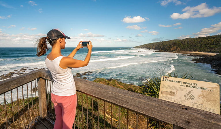 A woman taking a photo of the view from Three Sisters walking track in Broken Head Nature Reserve. Photo: John Spencer/DPIE
