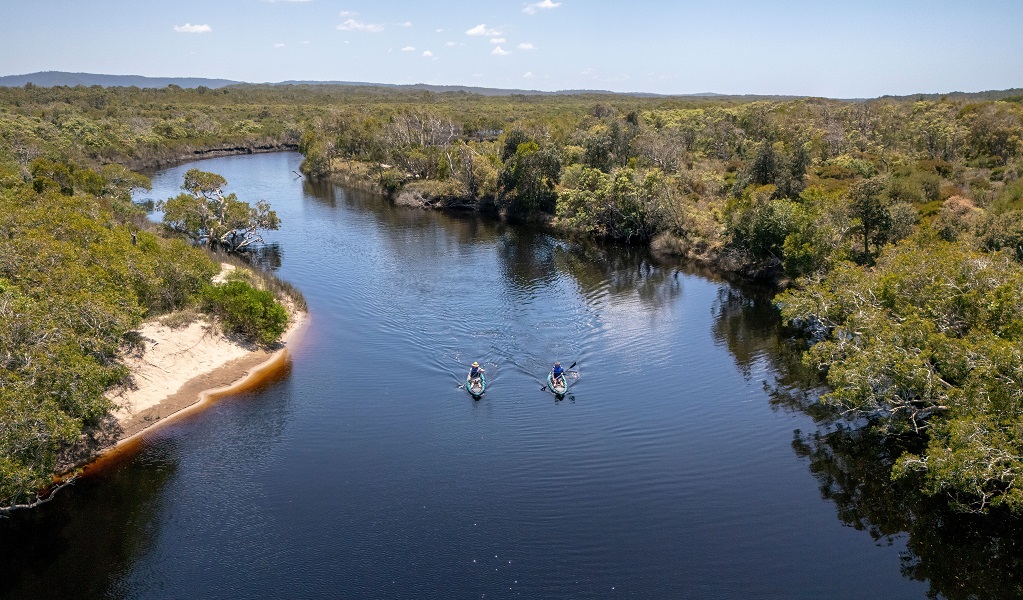 Aerial view of paddlers in a wider section of Jerusalem Creek, with the sky reflected in the water, Bundjalung National Park. Credit: John Spencer/DCCEEW &copy; DCCEEW