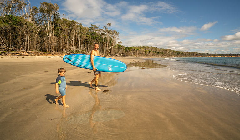 A father and young son head down to the water for a paddle, Woody Head campground, Bundjalung National Park. Photo: John Spencer/OEH