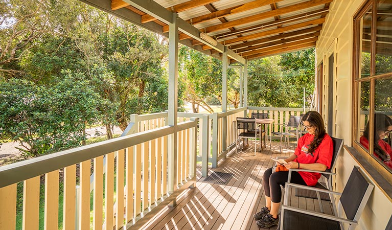 Cottage 6, woman reading on the verandah, Woody Head, Bundjalung National Park. Photo: John Spencer/OEH 