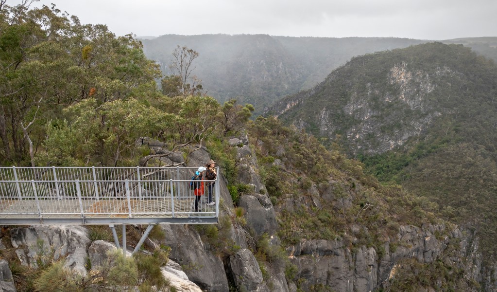 Two people enjoying the view at The Lookdown lookout surrounded by mountains in Bungonia National Park. Photo: John Spencer &copy; DCCEEW