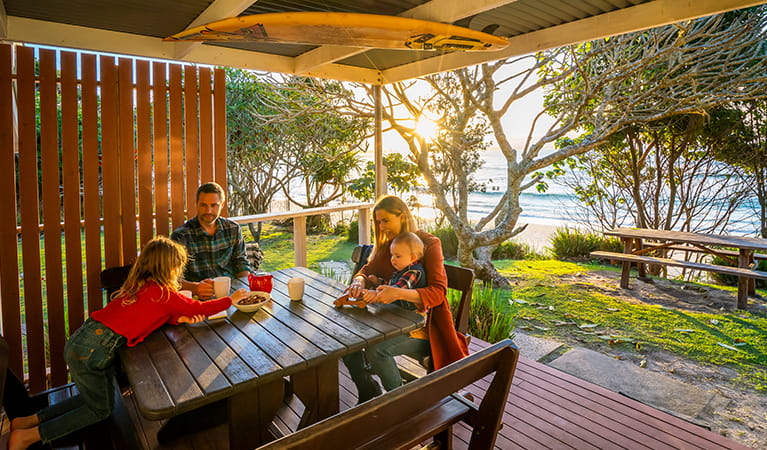 Family on the back deck of Partridge cottage overlooking Byron Bay beach. Photo: DPIE/John Spencer
