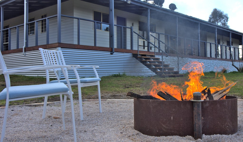 An outdoor firepit and chairs with Honeyeater Homestead in the background, in Capertee National Park. Photo: Steve Garland &copy; DPE