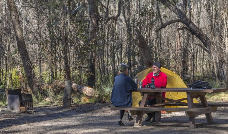 A couple sitting at a picnic table with their tent in the background at Barokee campground in Cathedral Rock National Park. Photo: Josh Smith &copy; DPE
