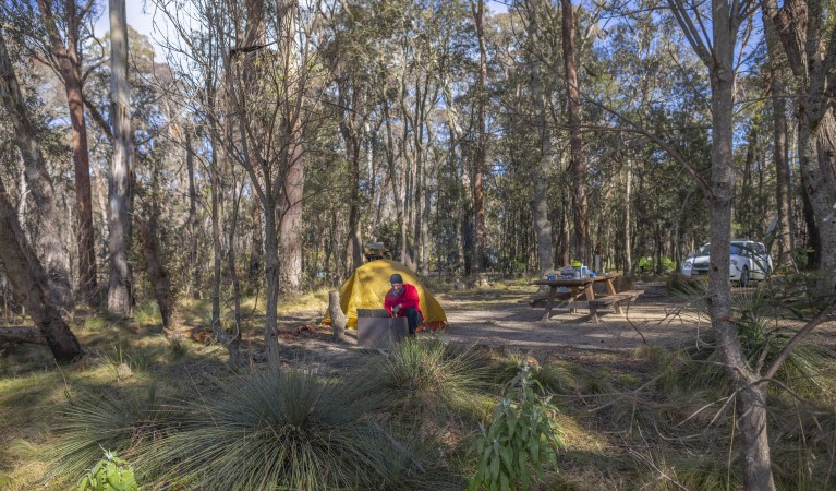 A man tends to the wood barbecue next to his tent at Barokee campground in Cathedral Rock National Park. Photo: Josh Smith &copy; DPE