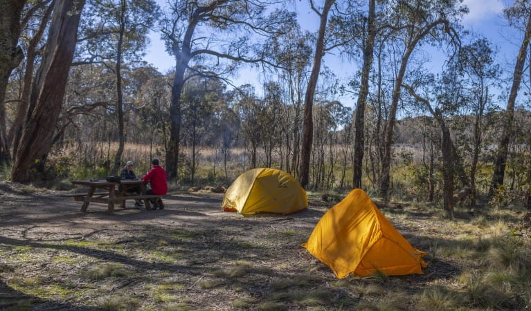 Two people sit at a picnic table with their tents in the foreground at Barokee campground, Cathedral Rock National Park. Photo: Josh Smith &copy; DPE