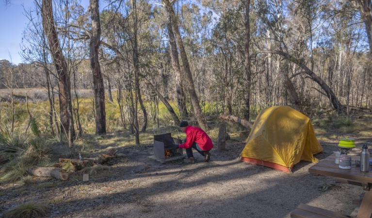 A man tends to the wood barbecue next to his tent at Barokee campground in Cathedral Rock National Park. Photo: Josh Smith &copy; DPE