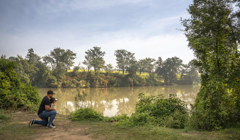 A father helping his daughter use binoculars to spot wildlife on the Hawkesbury River, at Cattai campground in Cattai National Park. Photo: John Spencer/OEH