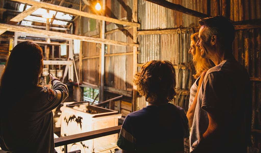 Family inside a corrugated iron shed building, looking at old mining equipment. Photo credit: Destination NSW &copy; Destination NSW