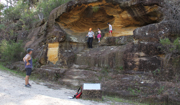 People beside a rock formation on Devines Hill walking track. Photo: John Yurasek