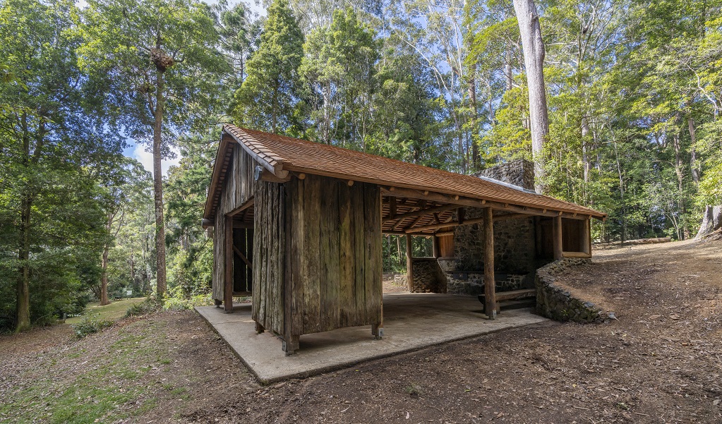 One side of the historic wooden picnic shelter, showing its gabled roof and timber frame at Never Never picnic area, Dorrigo National Park. Credit: John Spencer/DCCEEW &copy; DCCEEW