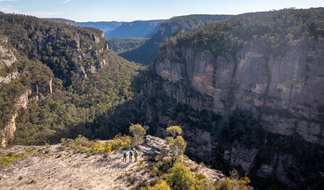 An aerial view of 3 hikers enjoying the view from Carne View lookout along Broad Swamp to Birds Rock walking track in Gardens of Stone State Conservation Area. Credit: John Spencer &copy; DCCEEW