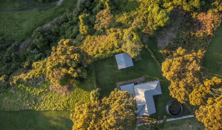 An aerial view of Baileys Cottage surrounded by trees in Glenrock State Conservation Area. Photo: John Spencer &copy; DPIE