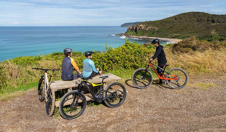 3 cyclists taking a break at a picnic table. Photo: John Spencer &copy; DPE