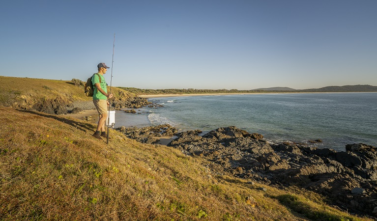 A fisherman walking along the coastline at Goolawah National Park. Photo: John Spencer/OEH