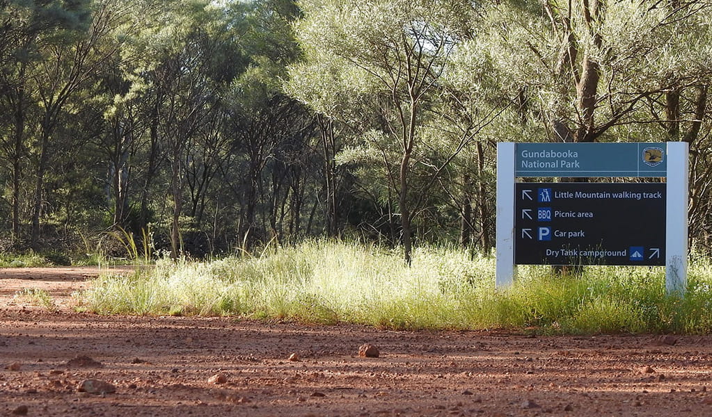 Photo of a sign on a red dirt road pointing to Dry Tank campground and picnic area at Gundabooka National Park. Photo credit: Jess Ellis/DPE &copy; DPE