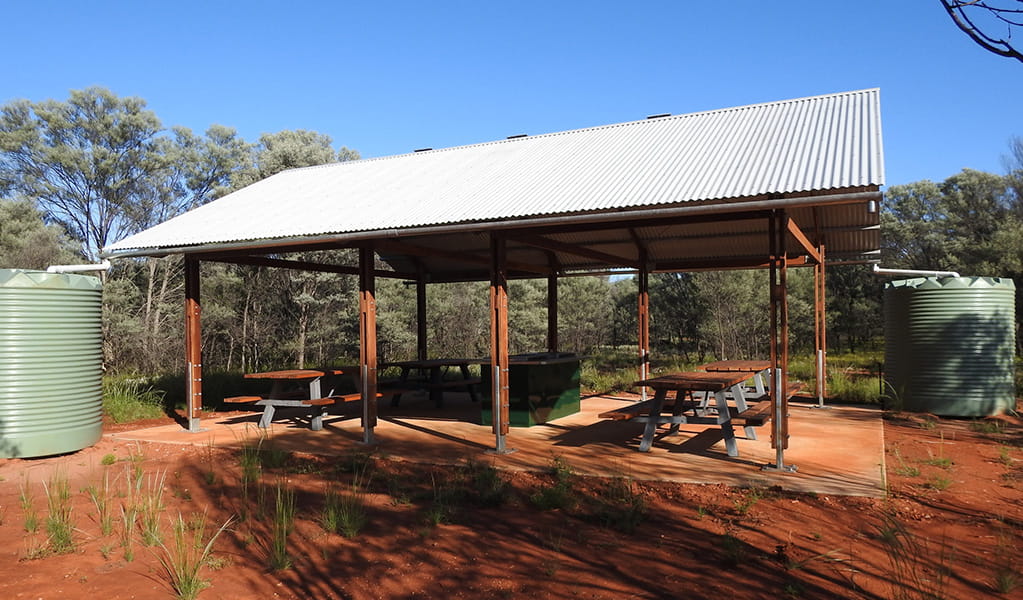 Photo of picnic tables and a barbecue under a shelter at Dry Tank campground and picnic area at Gundabooka National Park. Photo credit: Jess Ellis/DPE &copy; DPE