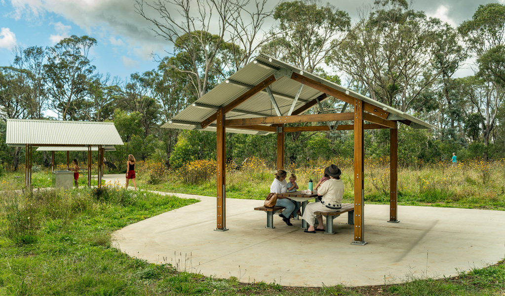 People at a picnic table at Ebor Falls picnic area, Guy Fawkes River National Park. Photo: David Waugh, &copy; DCCEEW