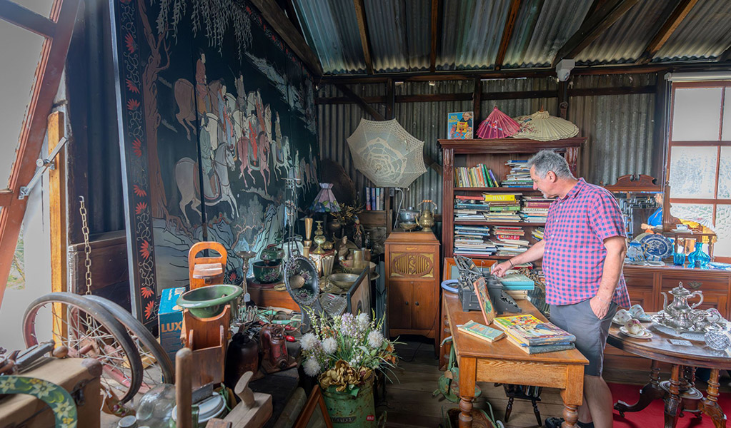 A visitor browsing antiques for sale at Gold Rush Antiques in the historic Corneys Garage, Hartley Historic Site. Credit: John Spencer &copy; DCCEEW