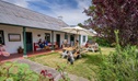 People eating at shaded tables on the lawn and garden outside The Postmistress Cafe and Store at Hartley Historic Site. Credit: John Spencer &copy; DCCEEW