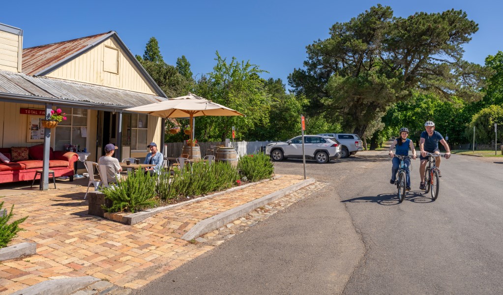 Visitors enjoy a coffee at General Store cafe as cyclists ride along the street in Hill End Historic Site. Photo: John Spencer/DCCEEW &copy; DCCEEW