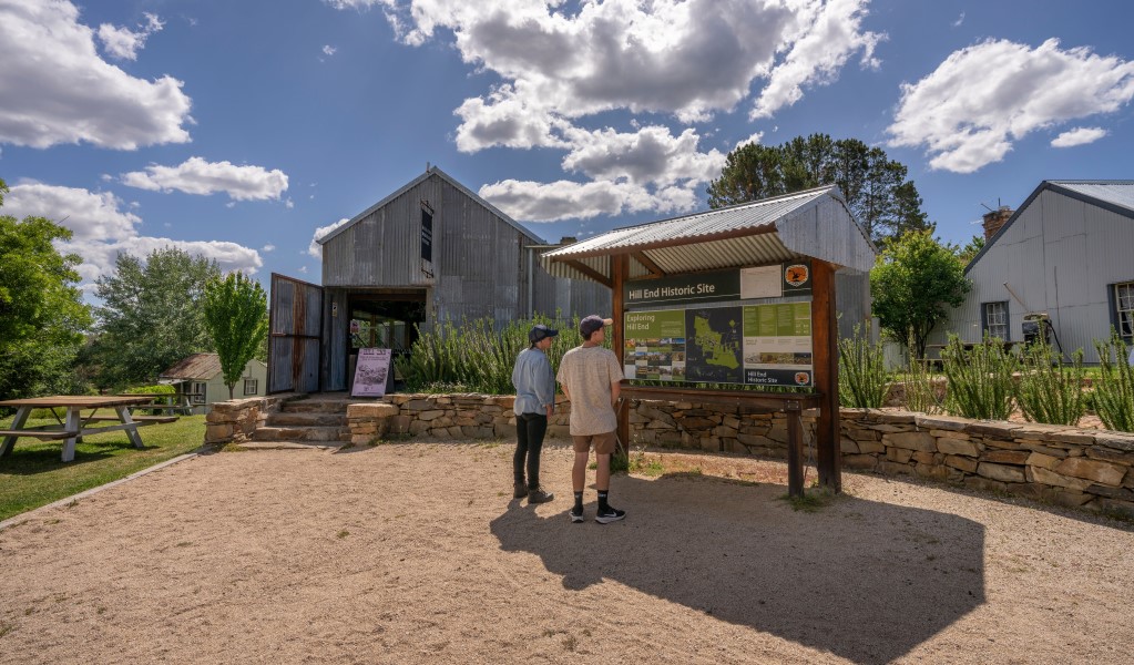 Two visitors pause to read the interpretive sign outside Hill End Heritage Centre. Photo: John Spencer/DCCEEW © DCCEEW