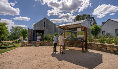 Two visitors pause to read the interpretive sign outside Hill End Heritage Centre. Photo: John Spencer/DCCEEW © DCCEEW