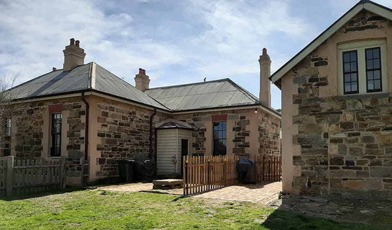 Exterior of the Post Office Residence and The Stables, with a small fence separating the two buildings. Photo credit: Lisa Menke. <HTML>&copy; DPIE