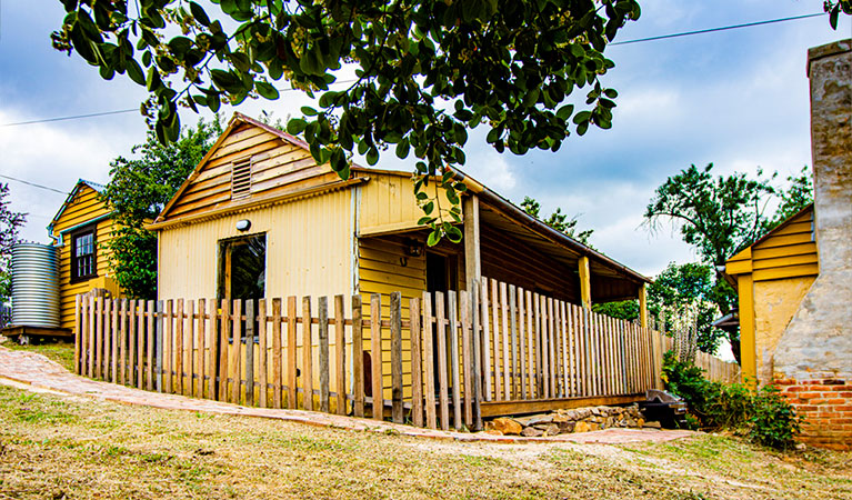 The exterior of Sydney Hotel Cottage surrounded by picket fence under trees in Hill End Historic Site. Photo: Steve Garland &copy; DPIE