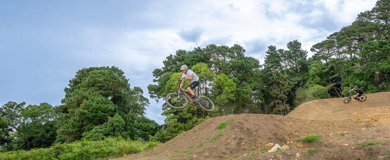Rider gets air off a jump on Kembla mountain bike trails. Credit: John Spencer © DCCEEW