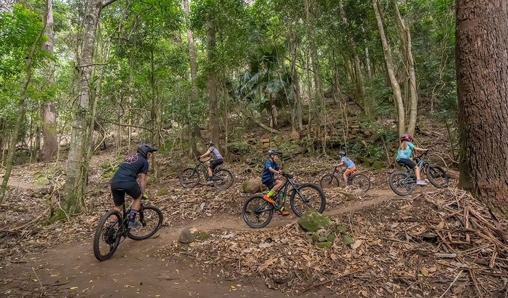 Riders of all ages and abilities ascend a one-way mountain bike trail. Credit: John Spencer © DCCEEW