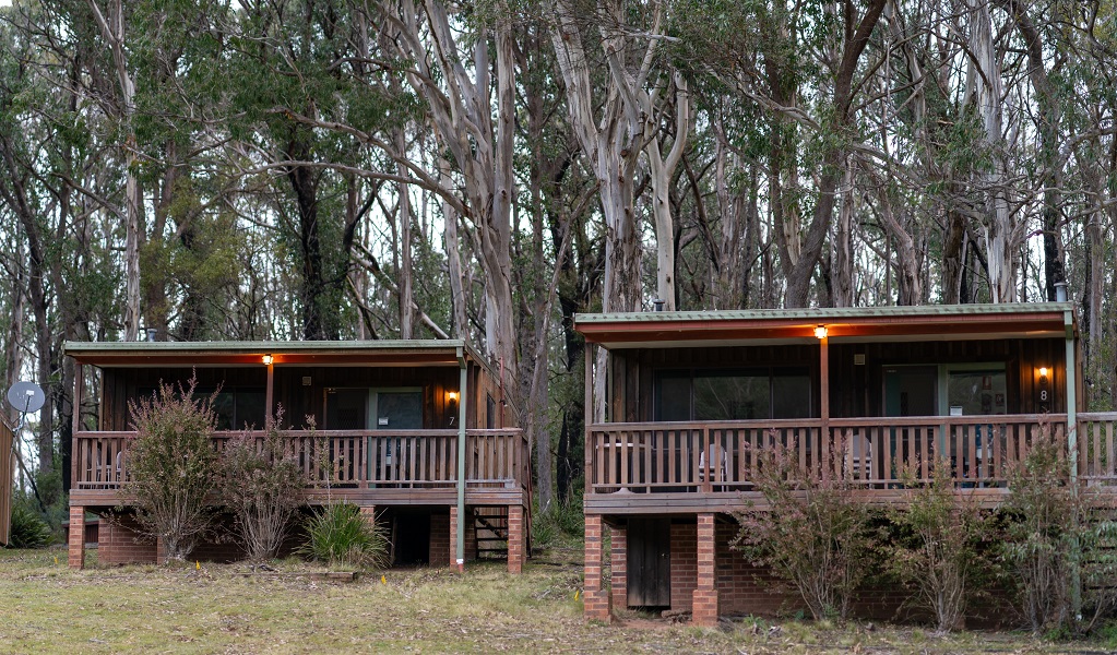 Exterior view of Binda Bush Cabins, with outside lights on in the dusk, Jenolan Karst Conservation Reserve. Photo: Jenolan Caves &copy; DPE 