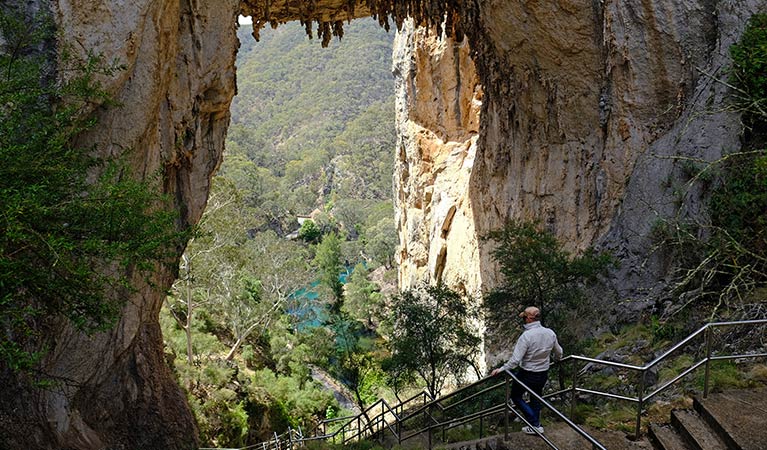 A man descends stairs under Carlotta Arch, in Jenolan Karst Conservation Reserve. Photo: Elinor Sheargold &copy; DPE