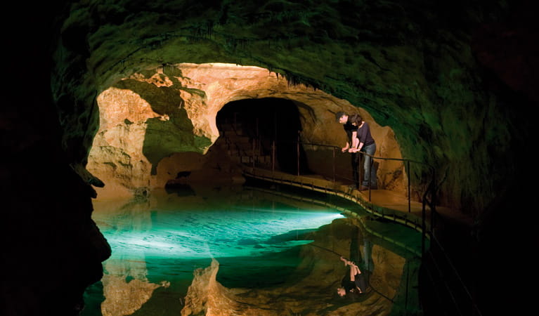 A man and woman look into a pool of water in a limestone cave at Jenolan Karst Conservation Reserve. Photo: Jenolan Caves Trust