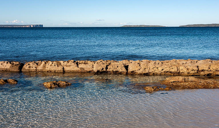 Clear water and rocks on the shore of Hyams Beach, Jervis Bay National Park. Photo: Michael Van Ewijk &copy; DPIE