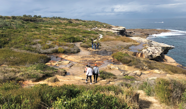 Walkers make their way along a sandstone section of path with ocean views. Credit: Natasha Webb &copy; Natasha Webb