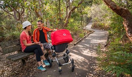 People sitting down on a timber bench with their pram in La Perouse area, Kamay Botany Bay National Park. Photo: John Spencer &copy; OEH