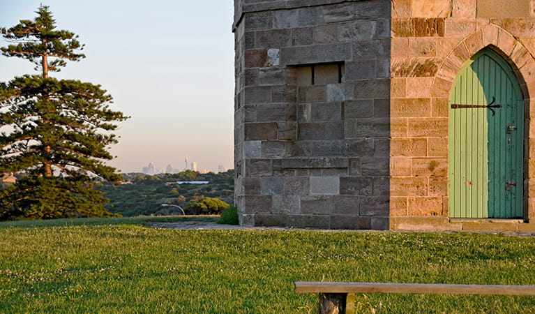 Detail of stone masonry and doorway of Macquarie watchtower, set on a grass lawn, with a pine tree in the background. Photo: Kevin McGrath/DPIE
