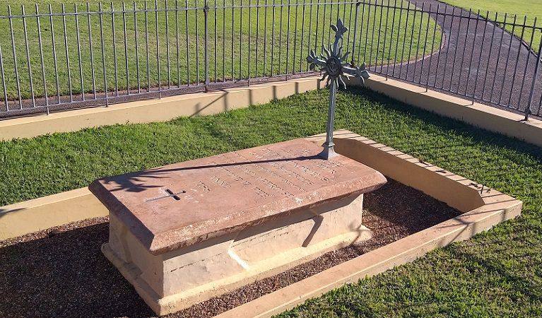 Close up of tomb showing metal cross and tomb inscription, within a grassy fenced area, in Kamay Botany Bay National Park. Photo: Stacy Wilson/DPIE