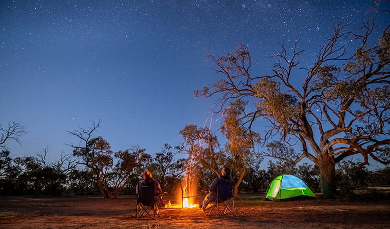 Campers stargazing by the fire at Emu Lake campground in Kinchega National Park. Photo: John Spencer/DPIE