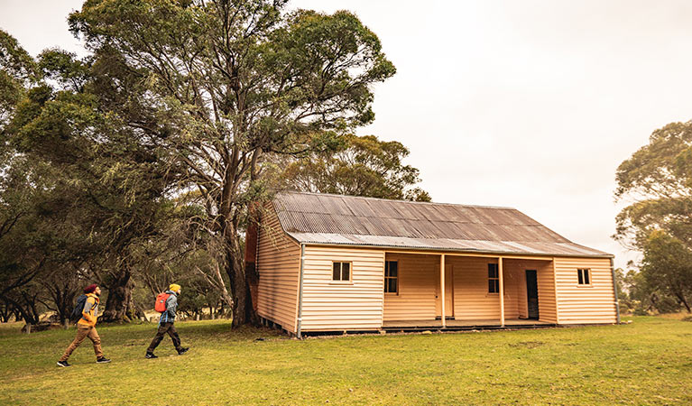 Two men walk towards Long Plain Hut in the High Plains area of Kosciuszko National Park. Photo: Robert Mulally/OEH