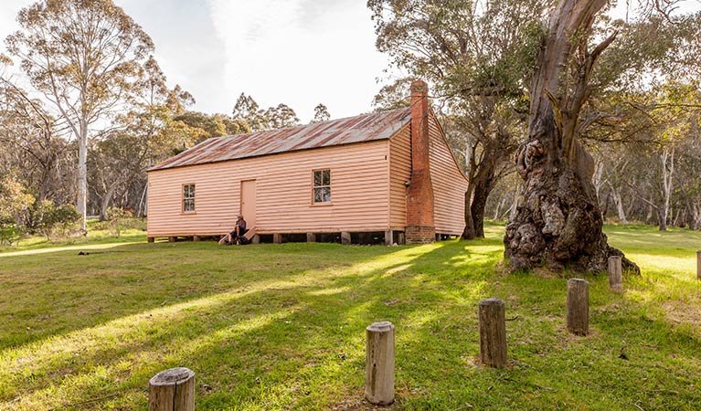 A man sits on steps outside Long Plain Hut, High Plains area, Kosciuszko National Park. Photo: Murray Vanderveer/OEH.