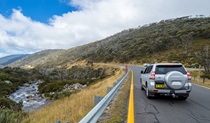 A 4WD vehicle drives towards Thredbo on Alpine Way, passing the Thredbo River near Dead horse Gap, Kosciuszko National Park. Photo: Murray Vanderveer/DPIE