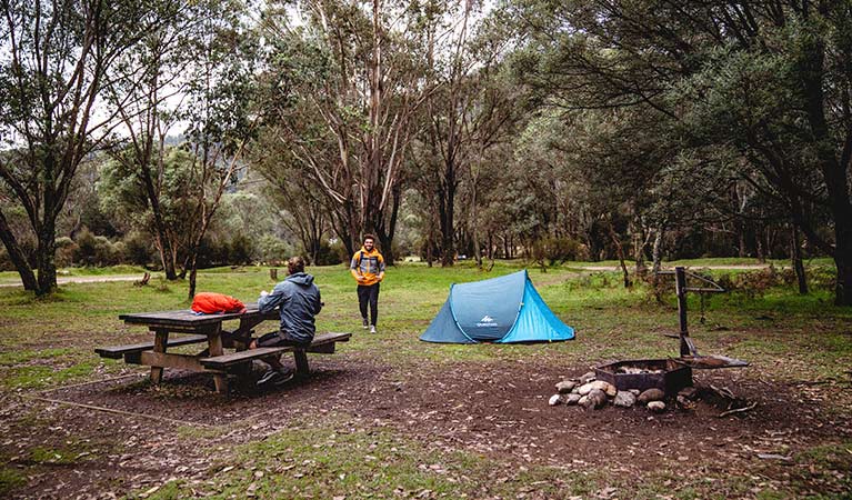 A man sits at a picnic table next to a tent at Geehi Flats campground, Kosciuszko National Park. Photo: Robert Mulally/OEH