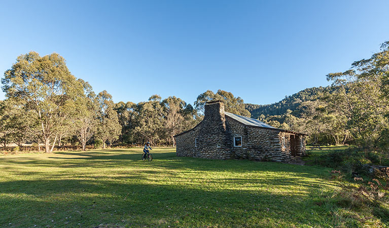 A cyclist rides past Geehi Hut, Kosciuszko National Park. Photo: Murray Vanderveer/OEH