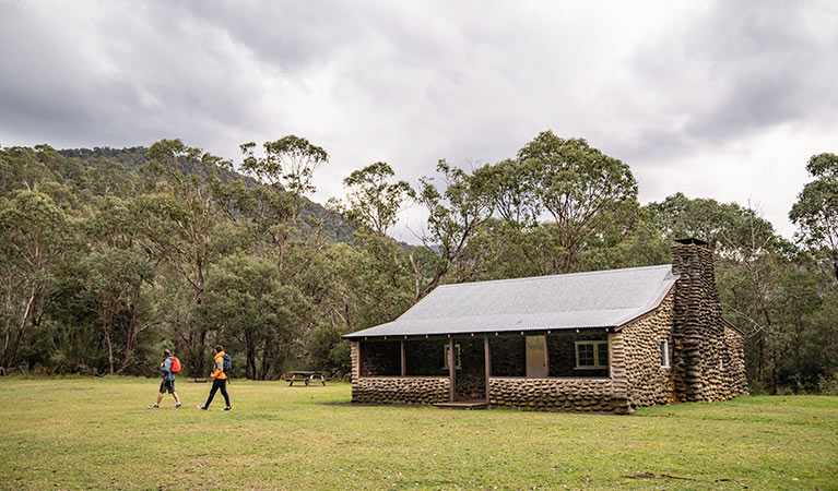 2 men walk across grass next to Geehi Hut, in Kosciuszko National Park. Photo &copy; Robert Mulally